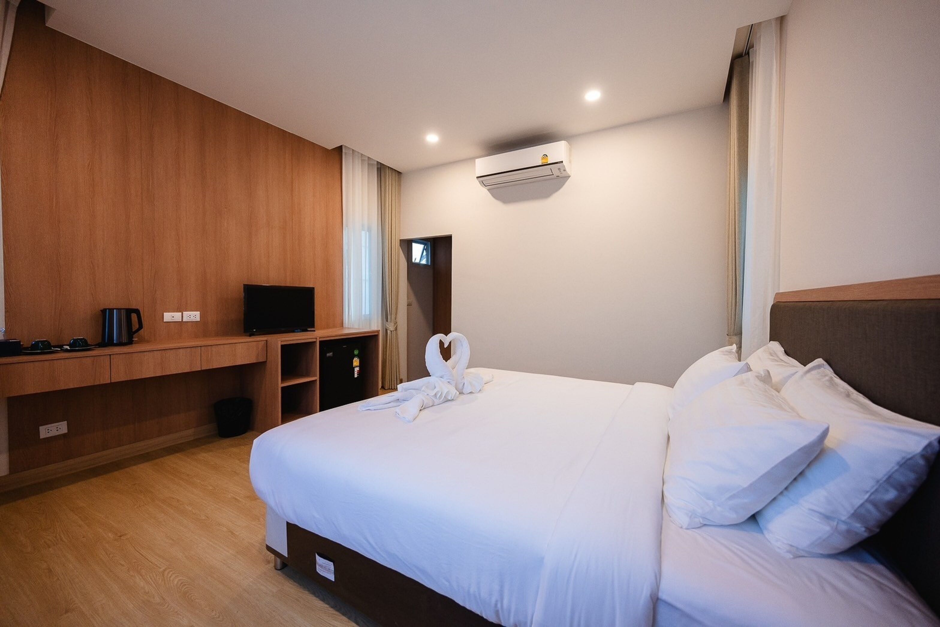 Een hotelkamer met een groot bed, een flatscreen televisie, een koffiezetapparaat en een wandairconditioner.