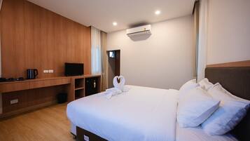 Een hotelkamer met een groot bed, een flatscreen televisie, een koffiezetapparaat en een wandairconditioner.