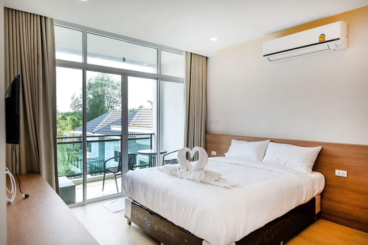 Habitación de hotel con una cama grande, televisión y balcón con vistas al exterior.