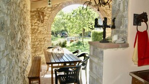 Eine Terrasse im Freien mit Steinmauern, einem Holztisch und Stühlen.