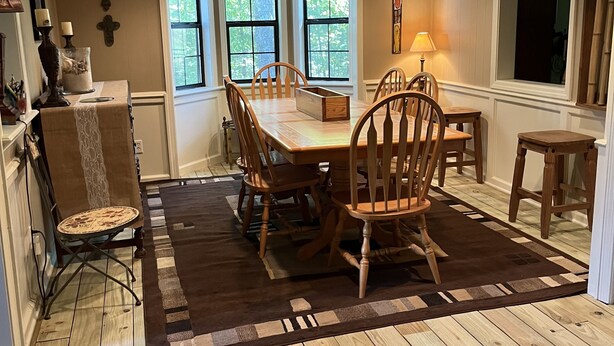A dining area with a wooden table and chairs, a ceiling fan, and large windows. - Southern Charm and Convenience: Perfect VRBO Retreat Near Ole Miss and Tupelo. (Pontotoc)