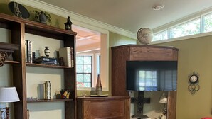 A living room with a fireplace, leather sofa, wooden shelves, and a television. - Southern Charm and Convenience: Perfect VRBO Retreat Near Ole Miss and Tupelo. (Pontotoc)