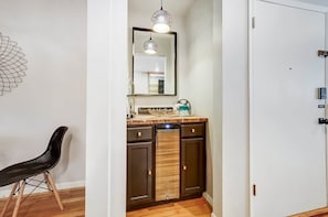 A modern kitchen with dark cabinets, a wooden countertop, a hanging light fixture, and a chair. - Cincinnati 2BR Corporate Stay, Garage Parking (Cincinnati)