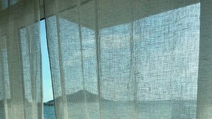 Una vista attraverso tende leggere su un balcone con vista su una distesa d'acqua.