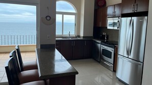 Una cucina moderna con vista sul mare, elettrodomestici in acciaio inossidabile e un'area pranzo anch'essa con vista.