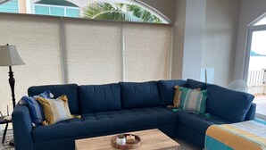 Un soggiorno con un divano a divanetto blu scuro, un tavolino in legno e una coperta colorata.