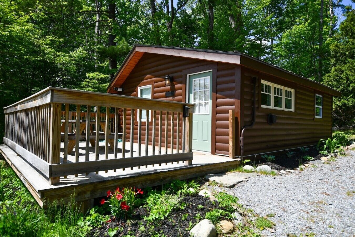 A small cabin with a wooden deck, a door, and windows.