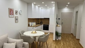 Un apartament modern amb zona de menjador, cuina i saló amb sofà.