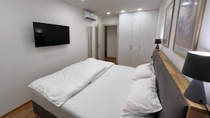 Un dormitori amb un llit, una televisió, un armari i una làmpada.