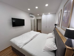Une chambre à coucher avec un lit, une télévision, une armoire et une lampe.