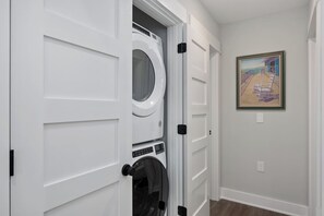 A laundry room with a washer and dryer, a door with a handle, and a framed painting on the wall.