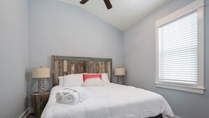 A bedroom with a bed, two bedside lamps, a window with blinds, and a ceiling fan. - Welcome to Waves of Fun Single Level, Dog Friendly (Corolla)