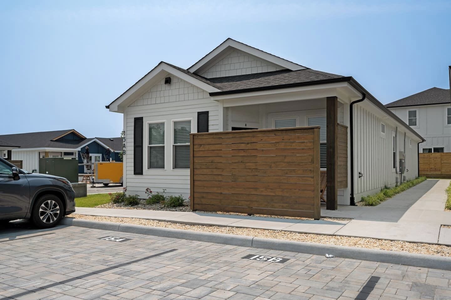 A modern single-story house with a garage, a wooden fence, and a paved driveway.