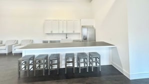 A modern kitchen with a central island, bar stools, and white cabinetry. - Welcome to Waves of Fun Single Level, Dog Friendly (Corolla)