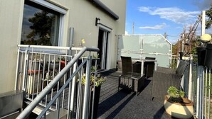 Une terrasse sur le toit, aménagée avec du mobilier d’extérieur, des plantes en pot et une rambarde en métal.