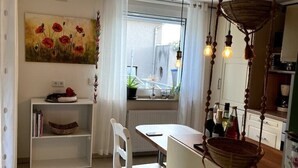 Un coin repas comprenant une table, des chaises, un luminaire suspendu et un tableau au mur.