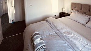 Une chambre d’hôtel comprenant un lit, une table de chevet, un miroir fixé au mur et une porte donnant sur une autre pièce.