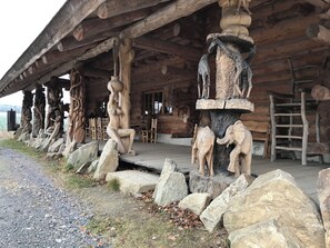 Un edificio rústico de madera con figuras talladas y grandes rocas.