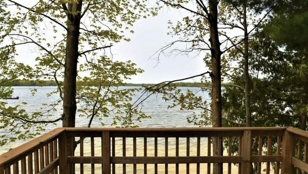 A wooden deck with a view of a lake. - Lake life at its finest with nearby outdoor adventures! Hunters and ORV welcome! (Baldwin)