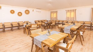 Una habitació àmplia amb diverses taules i cadires de fusta, disposades en estil de conferència.