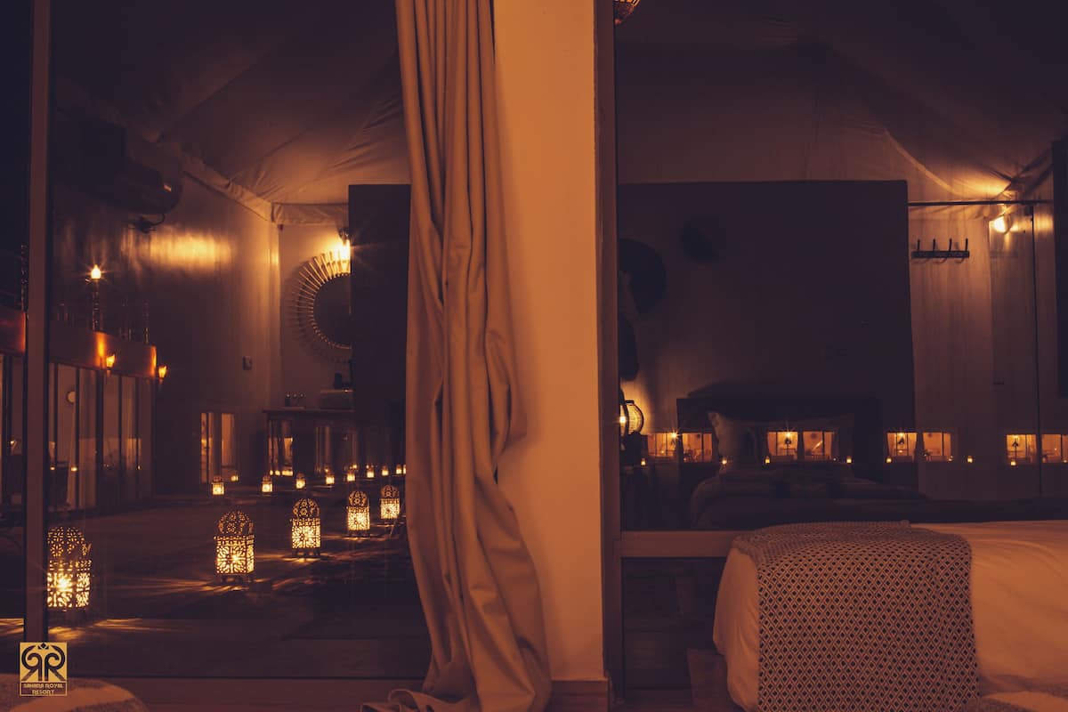 A dimly lit room with a bed, a hanging chair, and a small table.