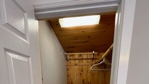 A narrow hallway with a wooden door, a wooden floor, and a ceiling with a skylight. - Walk to Beach - Pet friendly Cabin w/ Workspace (Lake George)