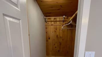 Un pasillo estrecho con puerta y suelo de madera, y techo con tragaluz.