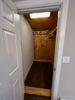 Un couloir étroit avec une porte en bois, un plancher en bois et un plafond doté d’un puits de lumière.