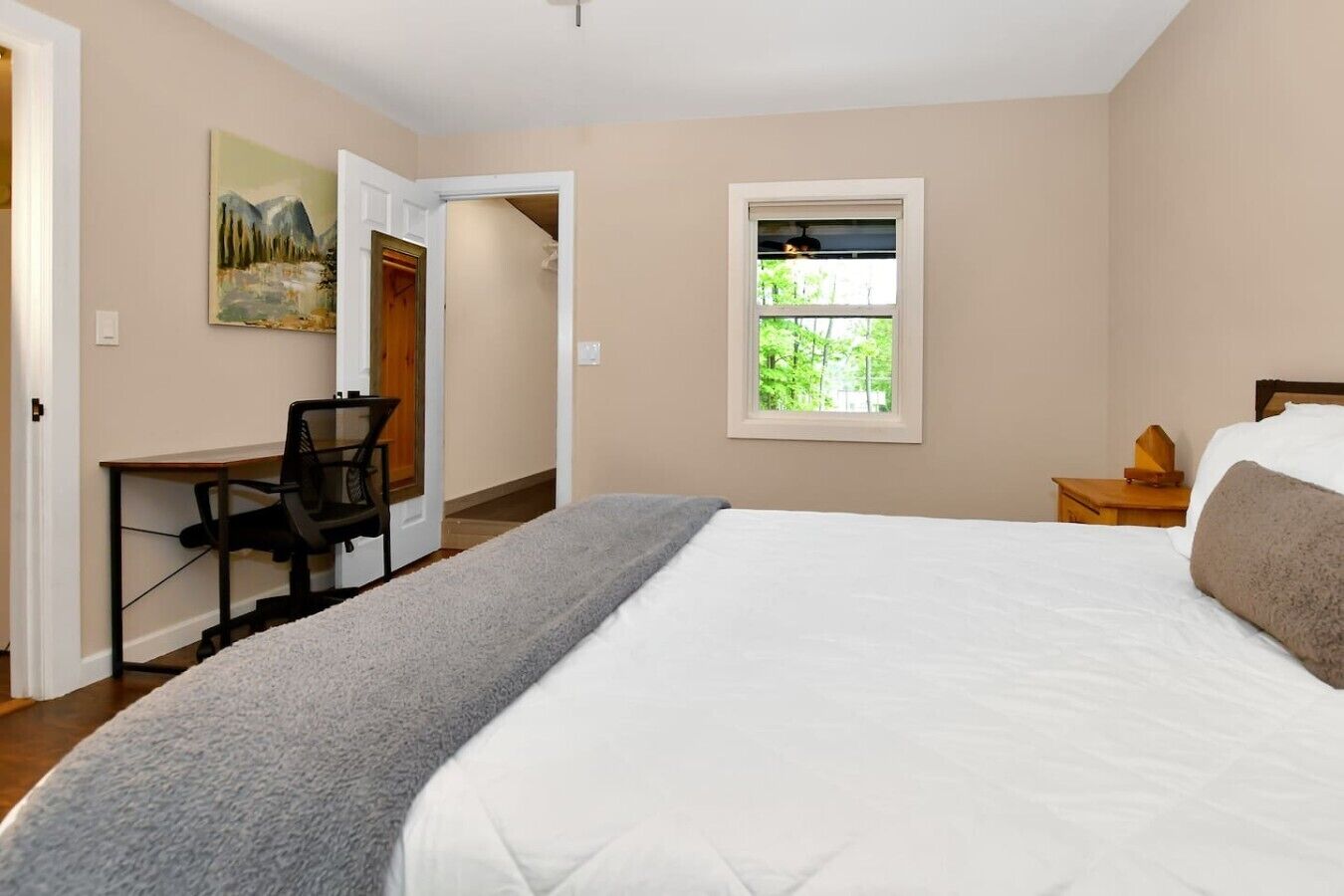 A bedroom with a bed, a desk, and a window.