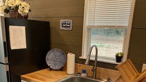 Eine Küche mit Holzarbeitsplatte, Spüle, Kühlschrank und einem Fenster mit Jalousien.