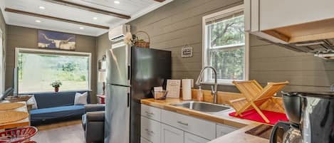 Cocina compacta con refrigerador, pileta y encimera de madera.
