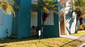A modern multi-story building with balconies, a gated entrance, and palm trees. - Cozy Condo in Cabo Rojo (Cabo Rojo)