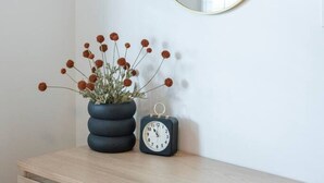 A wooden dresser with a potted plant and a wall-mounted round mirror.