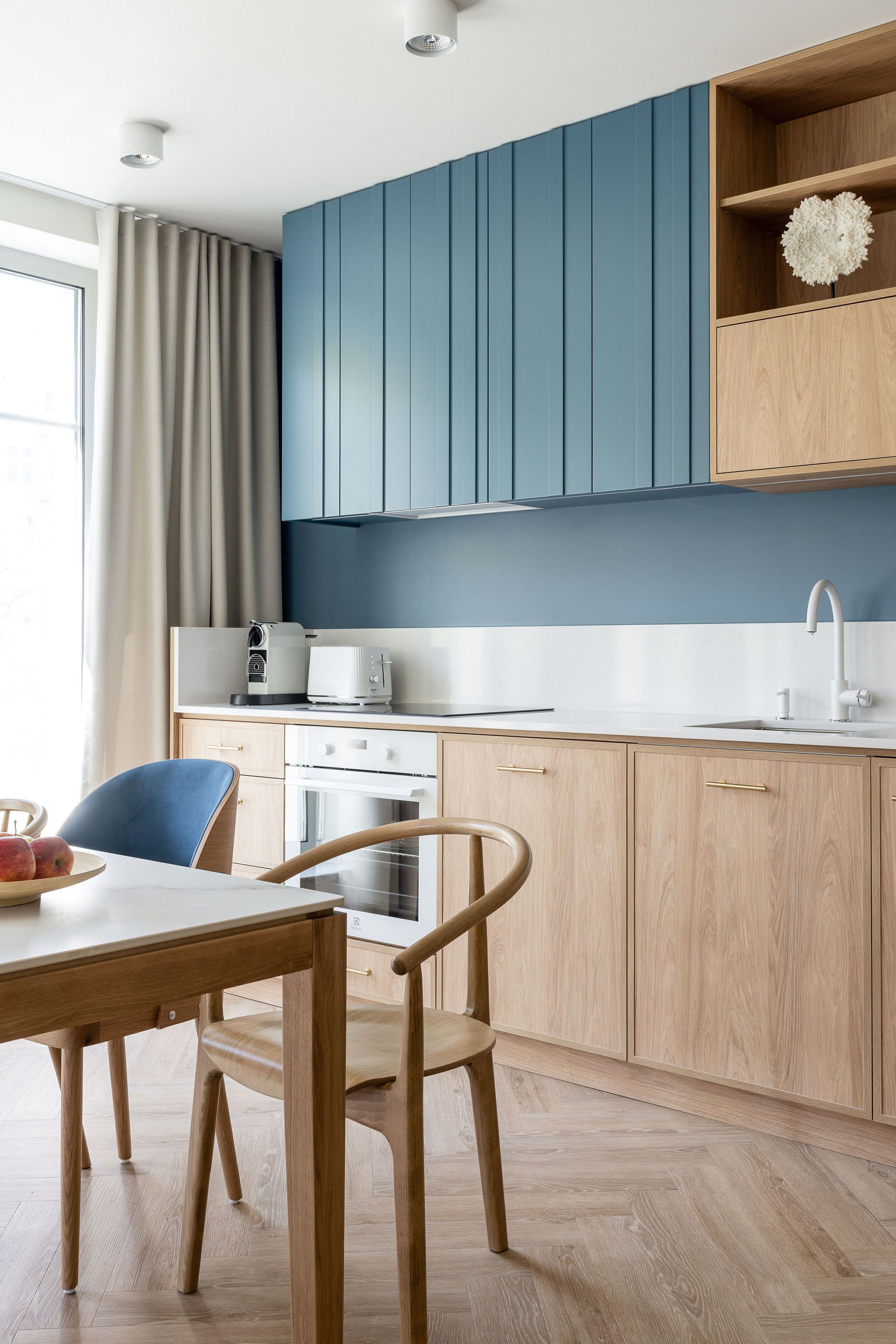 Une cuisine moderne avec des meubles en bois, un plan de travail blanc et un coin repas comprenant une table et des chaises.