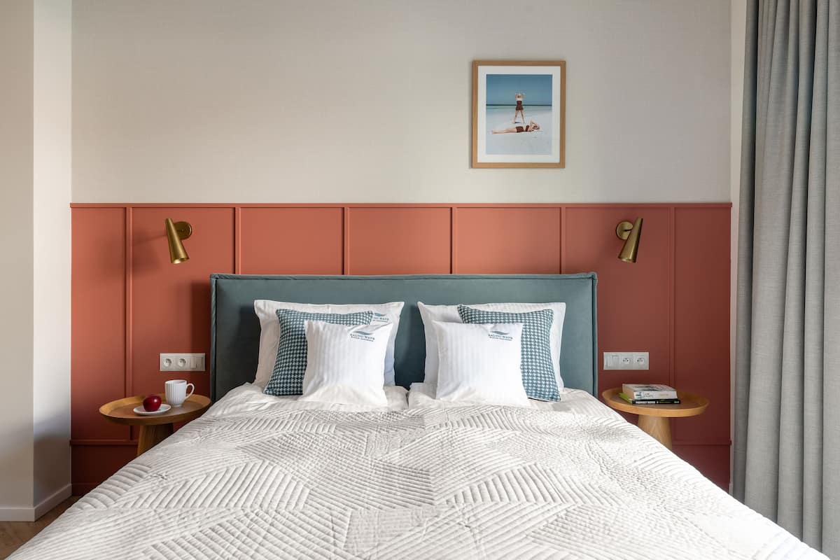 A neatly made bed with a patterned bedspread, two pillows, and a framed picture above it.