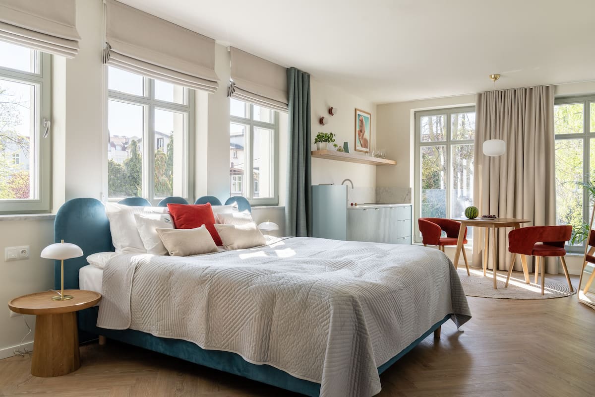 A bedroom with a large bed, a bedside table, a small round table, and a chair.