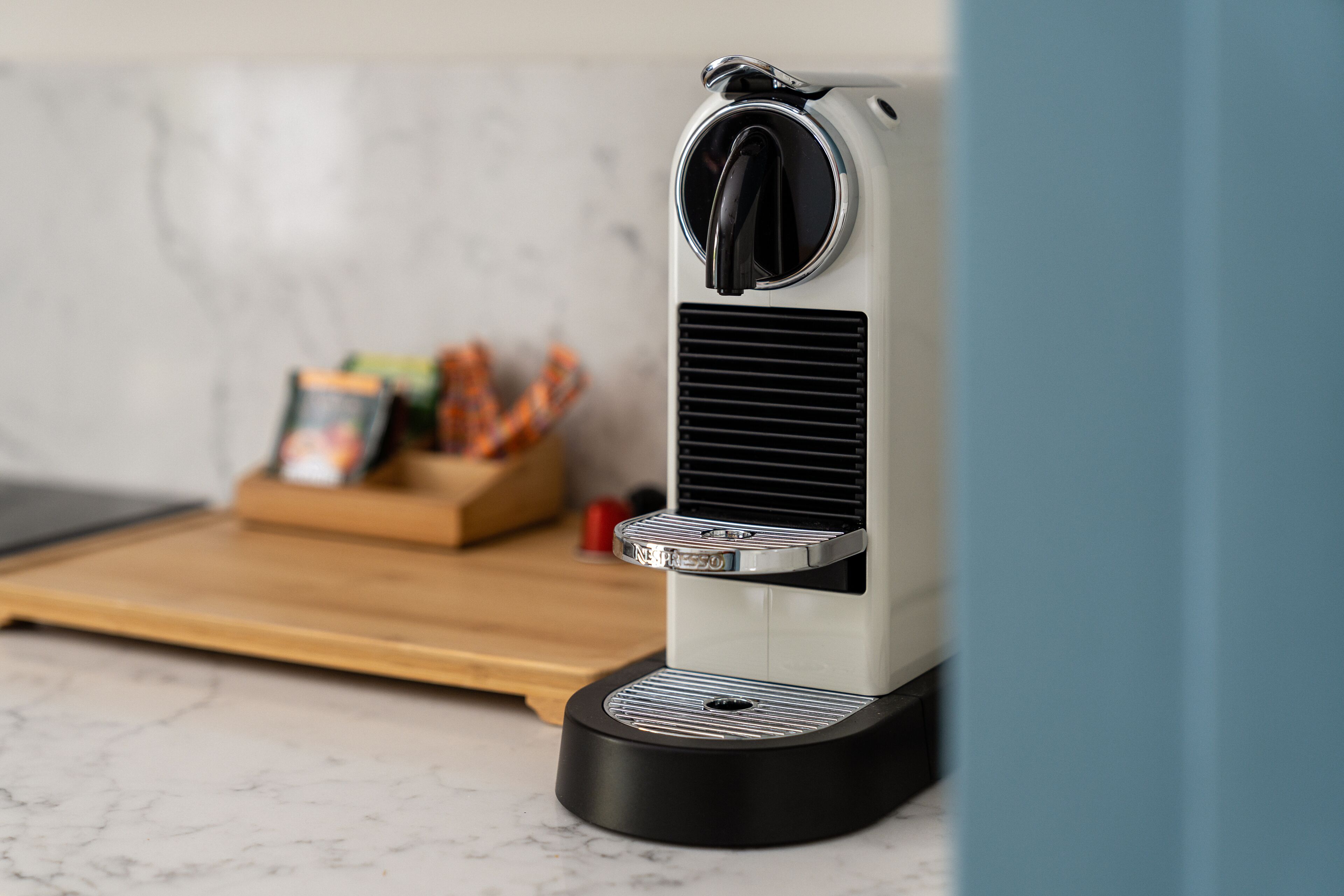 A coffee machine on a kitchen counter with a marble backsplash.