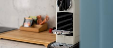 A coffee machine on a kitchen counter with a marble backsplash.