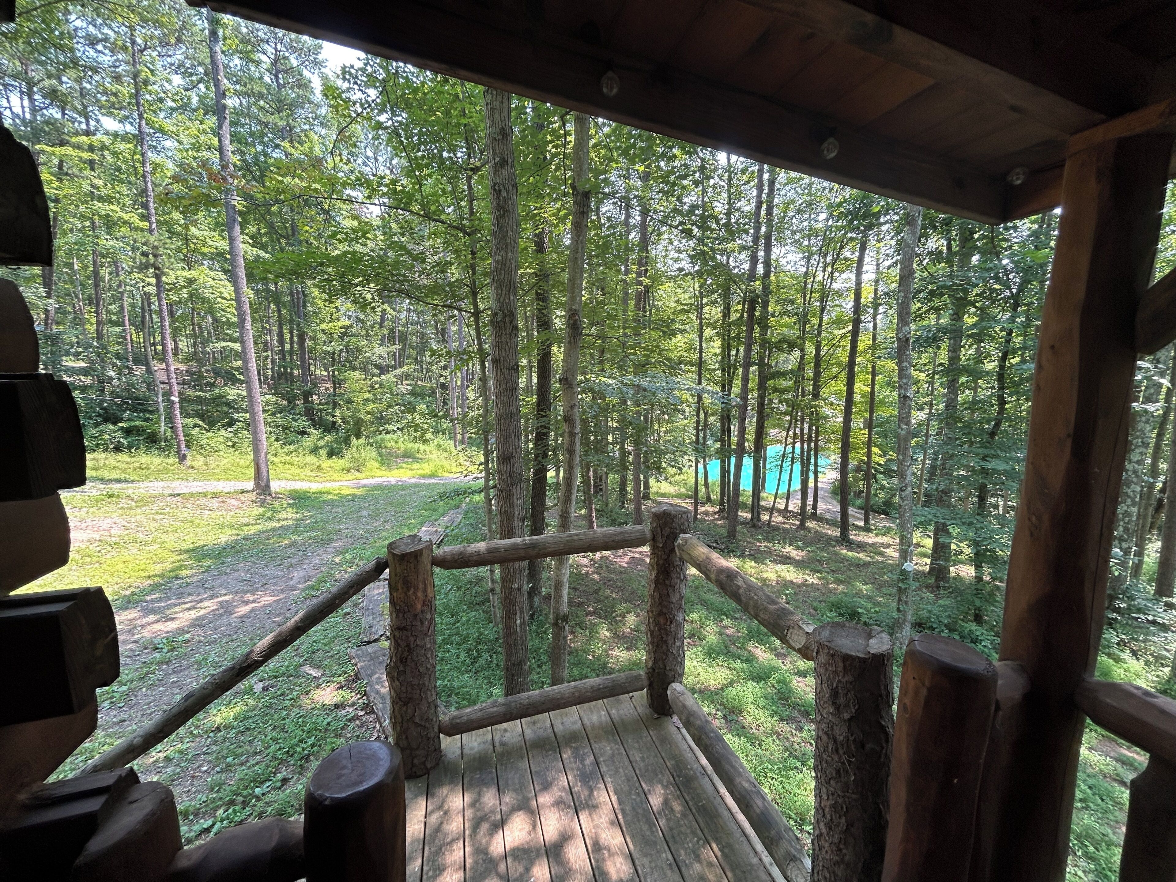 A wooden deck with a railing overlooking a forested area.