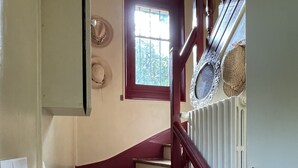 A staircase with a wooden handrail and a window with a view of trees. - Grande Maison Traditionnelle Proche de la Forêt (Brunoy)