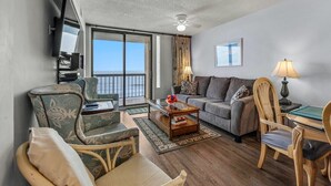 Un salon comprenant un canapé, des fauteuils, une table basse et un téléviseur.
