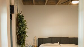 A bedroom with a bed, bedside table, and a hanging plant. - A fun & happy guesthouse with a loft!  Located 15 min. from Erskine College.  (Honea Path)