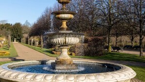 A fountain with multiple tiers and a circular basin, surrounded by a well-maintained garden with a pathway leading to a distant structure. - voco London Marylebone by IHG (London)
