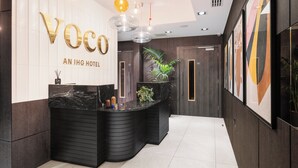 A reception area with a black counter, gold lettering for the hotel name, and modern pendant lighting. - voco London Marylebone by IHG (London)