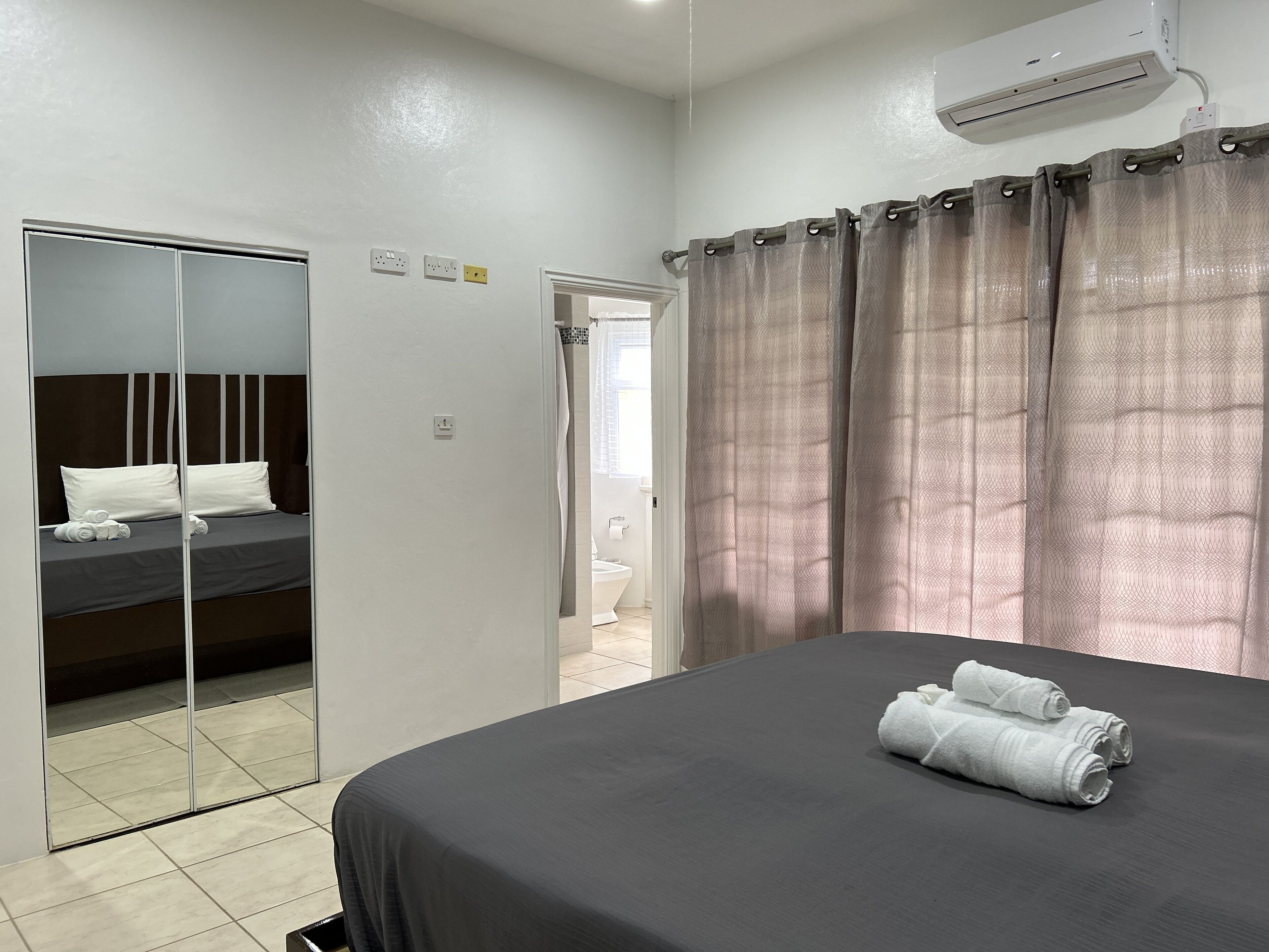 Una habitación de hotel con cama, espejo, zona de ducha y baño.