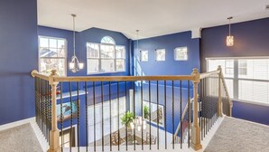 Ein mehrgeschossiges Interieur mit blauen Wänden, einer Holztreppe und Blick ins Freie.
