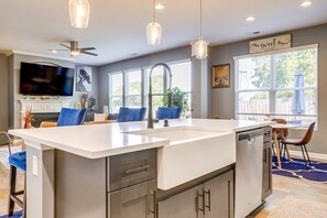 Una cocina moderna con una isla central, electrodomésticos integrados e iluminación colgante.