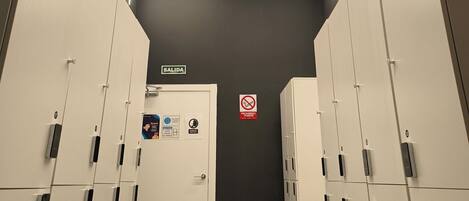 A modern elevator area with white lockers, a 'SALIDA' sign, and a 'No Smoking' sign.