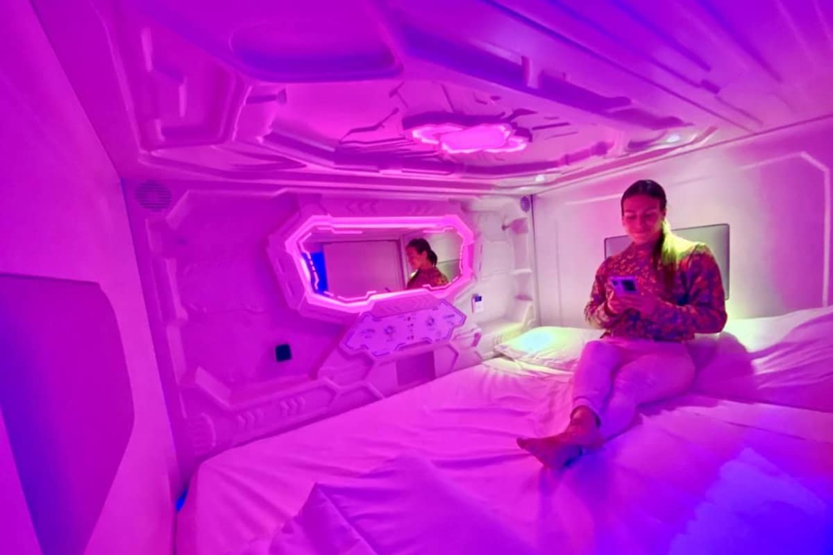 A room with a bed, a bedside table, and a mirror.