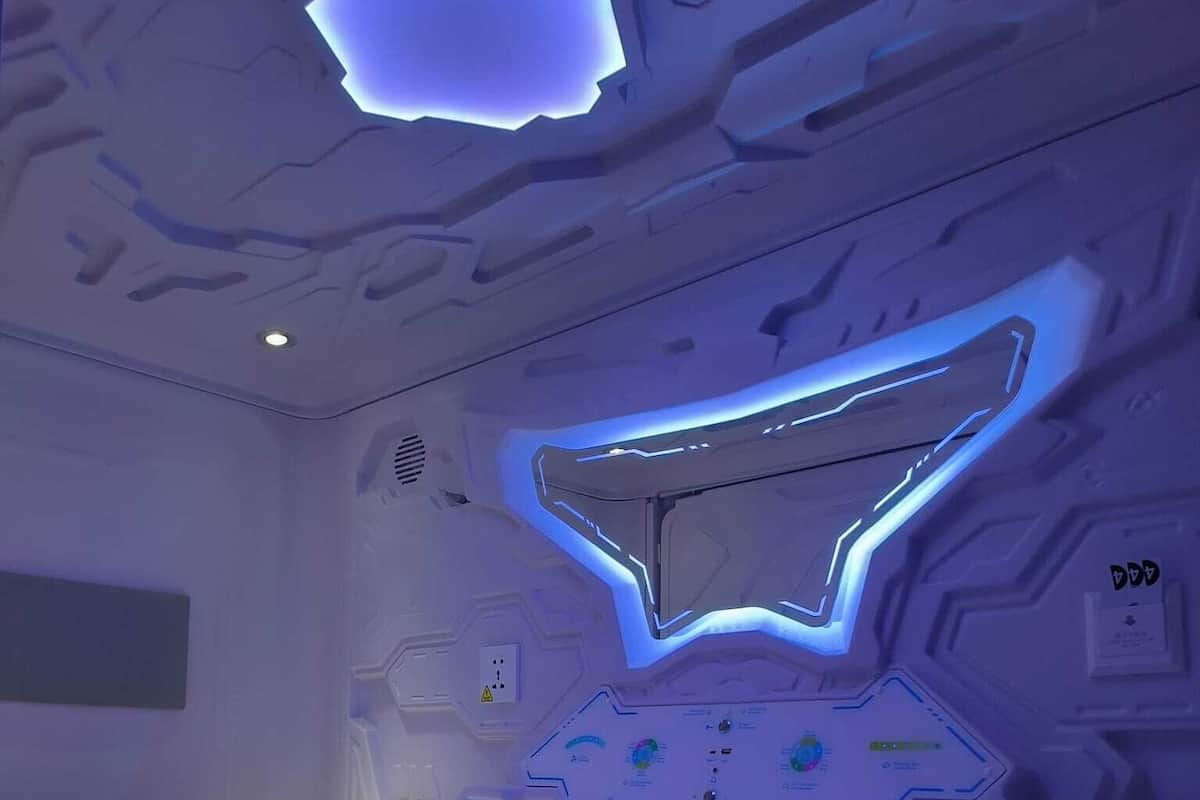 Un dormitorio futurista con cama, panel de control y un diseño de techo original.